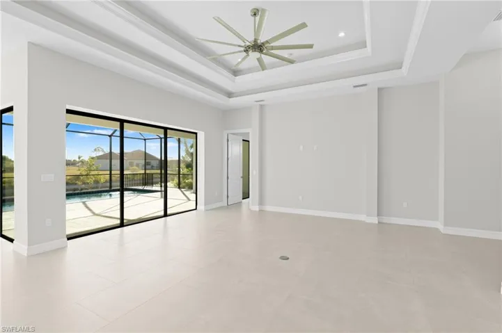 Empty room featuring a raised ceiling, a ceiling fan, and a sunroom