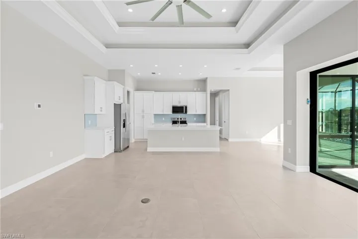 Unfurnished living room featuring a tray ceiling, ceiling fan, light tile patterned flooring, and recessed lighting