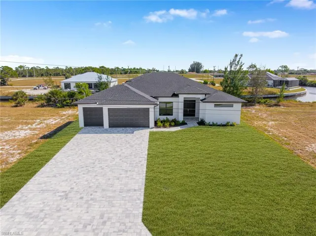 View of front of property with a front lawn, decorative driveway, an attached garage, and a shingled roof