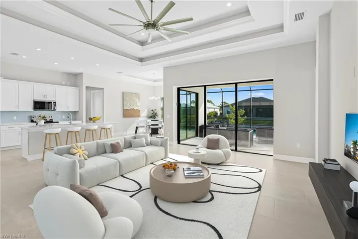 Living room featuring recessed lighting, a raised ceiling, a chandelier, and ceiling fan