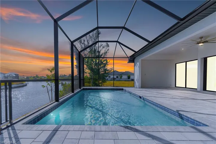 Outdoor pool featuring ceiling fan, a lanai, a sunroom, and a water view
