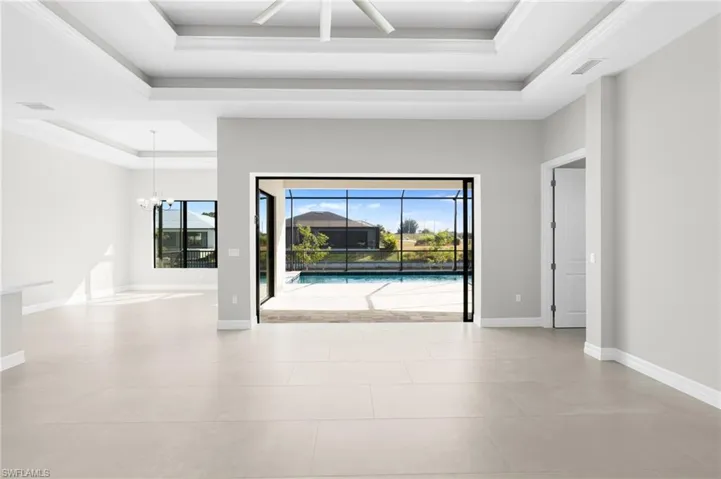 Spare room featuring a tray ceiling, a ceiling fan, a chandelier, and light tile patterned floors