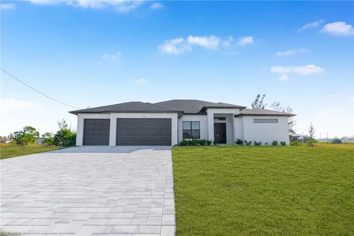 Prairie-style house with a front lawn, decorative driveway, a garage, and stucco siding