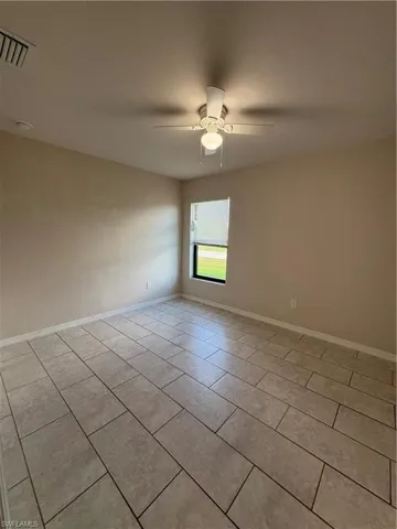 Empty room featuring ceiling fan and light tile patterned flooring
