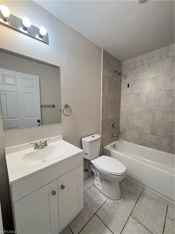 Full bathroom with tile patterned flooring, tiled shower / bath, toilet, and vanity