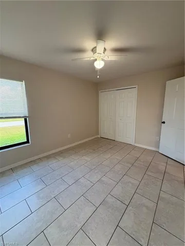 Unfurnished bedroom with a closet, light tile patterned floors, and ceiling fan