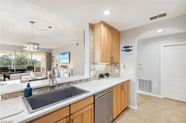 Kitchen with decorative backsplash, stainless steel dishwasher, light countertops, hanging light fixtures, and recessed lighting