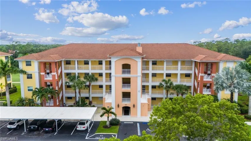 View of building exterior featuring covered and uncovered parking