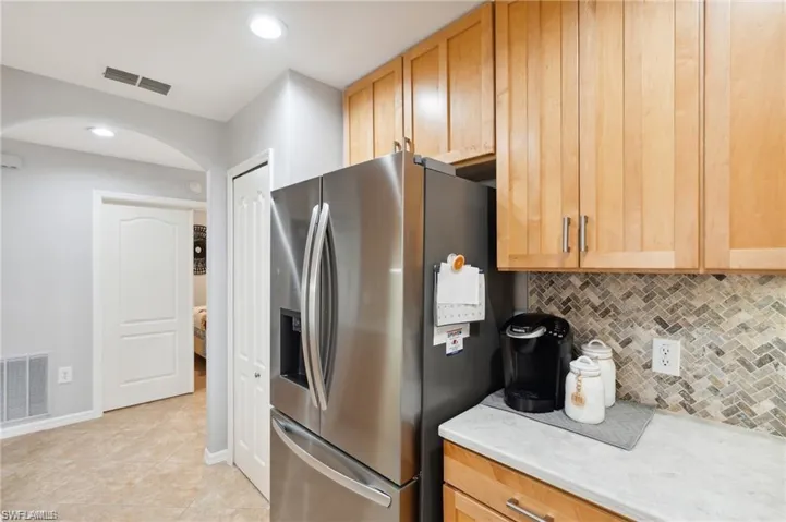 Kitchen with backsplash, stainless steel fridge with ice dispenser, light countertops, recessed lighting, and light tile patterned flooring