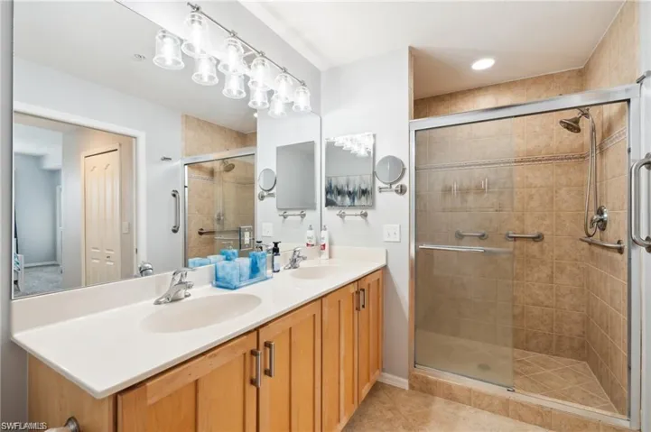Full bathroom with double vanity, a stall shower, and tile patterned floors