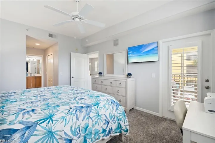 Carpeted bedroom with ensuite bath and ceiling fan