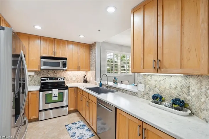 Kitchen featuring appliances with stainless steel finishes, tasteful backsplash, light countertops, recessed lighting, and light tile patterned floors