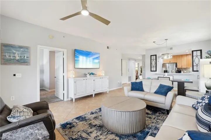Living room with light tile patterned flooring, a ceiling fan, and a chandelier