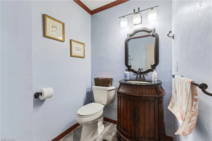 Bathroom featuring toilet, crown molding, and vanity