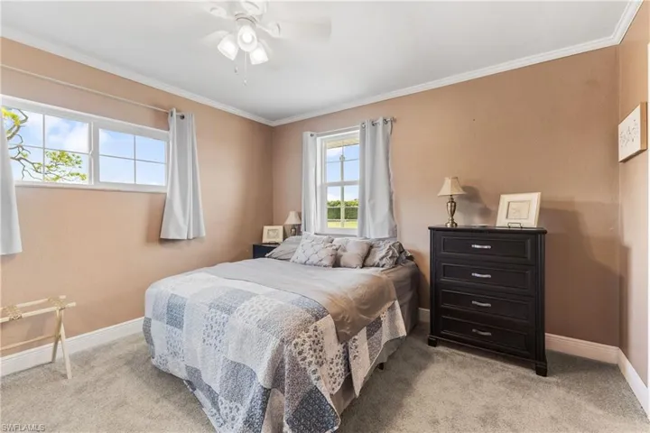 Carpeted bedroom featuring ceiling fan and ornamental molding