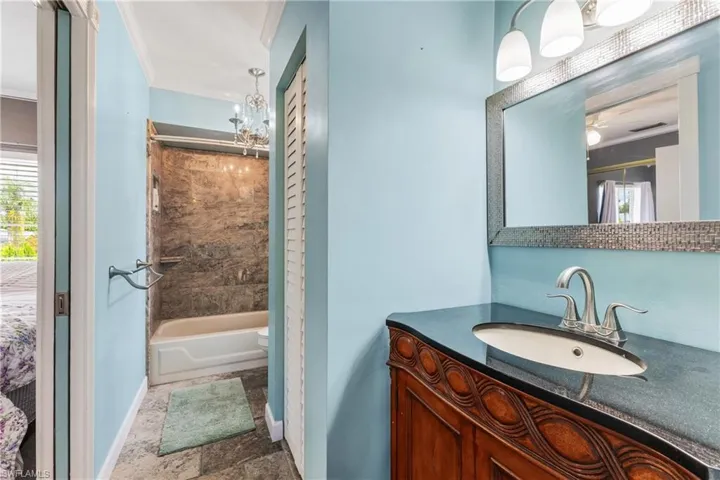 Full bathroom with crown molding, toilet, a chandelier, tub / shower combination, and vanity