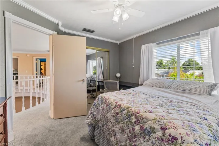 Bedroom with a closet, ceiling fan, carpet, and ornamental molding
