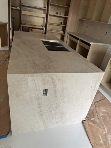 Kitchen with a kitchen island with sink and light stone counters