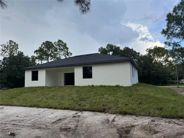 Back of property with stucco siding and a lawn