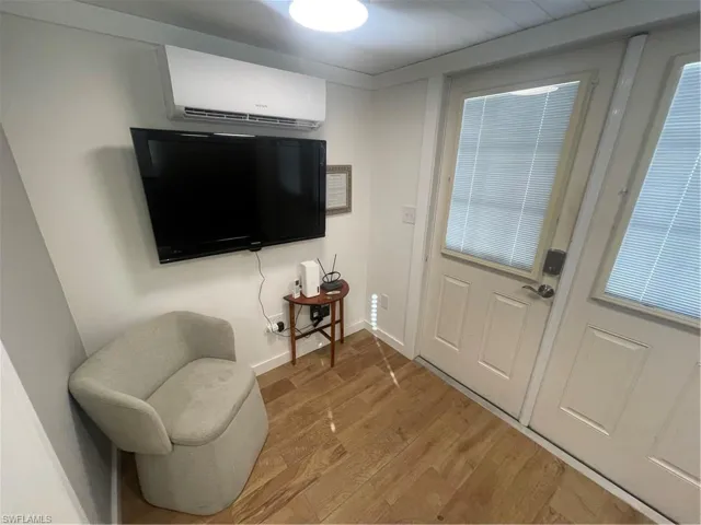 Sitting room with wood finished floors and an AC wall unit