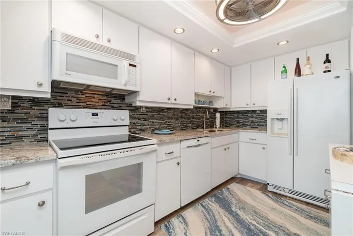 Kitchen featuring white appliances, crown molding, white cabinetry, and recessed lighting