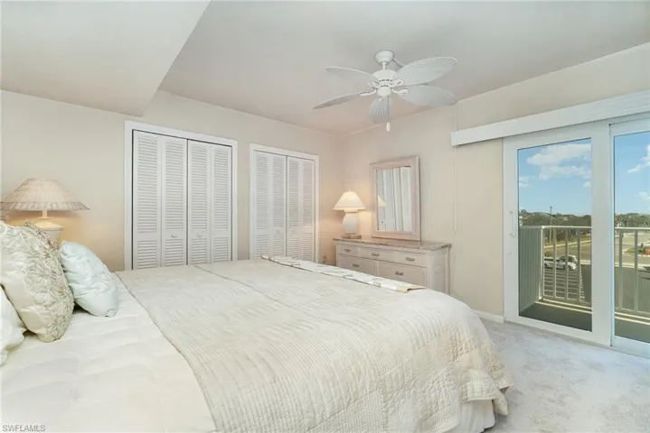 Carpeted bedroom featuring multiple closets, access to exterior, and ceiling fan