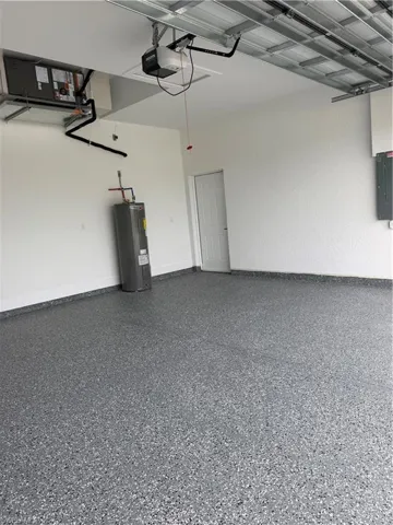 Garage featuring water heater, a garage door opener, and electric panel