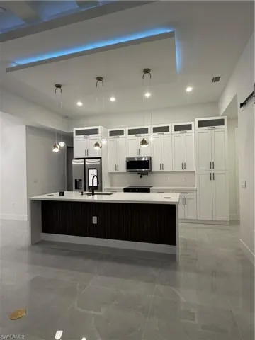 Kitchen featuring white cabinets, pendant lighting, glass insert cabinets, a barn door, and refrigerator