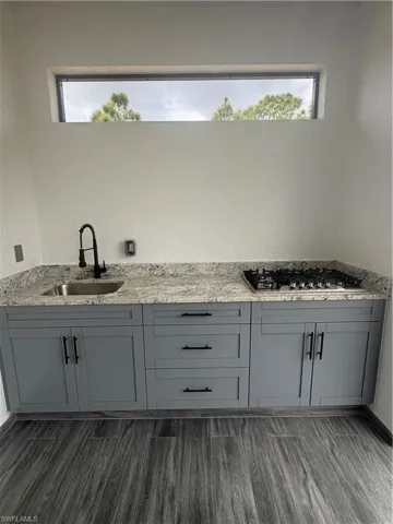 Full bathroom featuring double vanity, a textured wall, plenty of natural light, and dark wood-style flooring