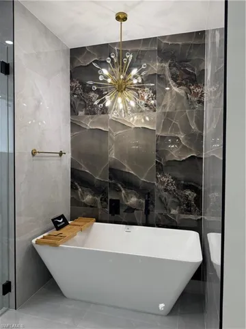 Full bathroom with tile walls, a freestanding bath, and stone wall