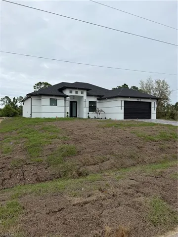 Prairie-style house featuring a shingled roof, an attached garage, concrete driveway, and stucco siding