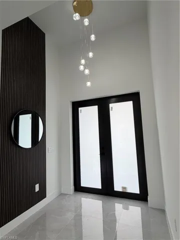 Foyer entrance featuring french doors, a high ceiling, and light marble finish floors