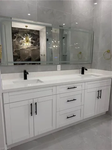 Full bathroom featuring double vanity and tile walls