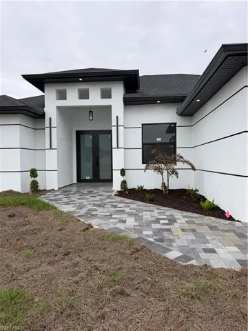 Entrance to property with french doors, stucco siding, and a shingled roof