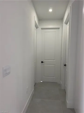 Hall with light tile patterned flooring and recessed lighting