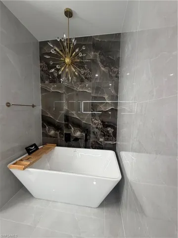 Bathroom featuring tile walls, a soaking tub, and stone wall
