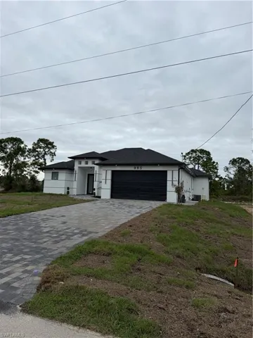 Prairie-style house with decorative driveway, stucco siding, an attached garage, and a front lawn