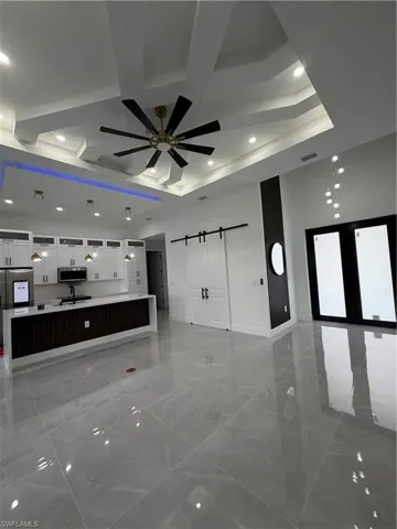 Unfurnished living room with a barn door, ceiling fan, recessed lighting, and coffered ceiling