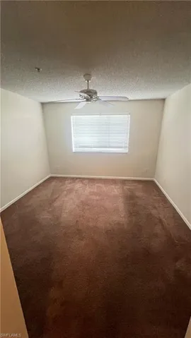 Carpeted spare room featuring a textured ceiling and ceiling fan