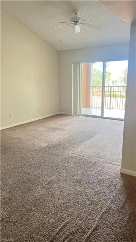 Carpeted empty room with a textured ceiling and ceiling fan