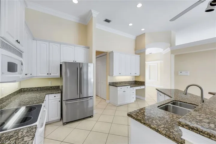 Kitchen with a center island and white cabinetry with all the major appliances.