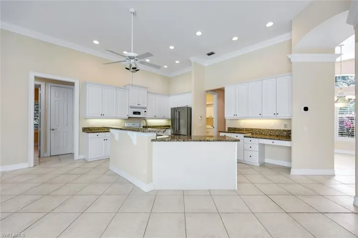 Kitchen featuring white cabinets, granite countertops, a large island, and all the major appliances.