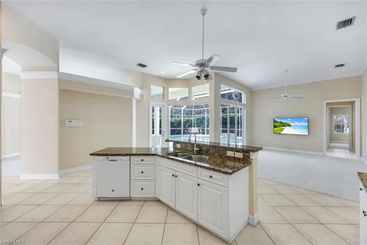 Kitchen overlooking the Family Room with a center island with white cabinetry and all the major appliances.