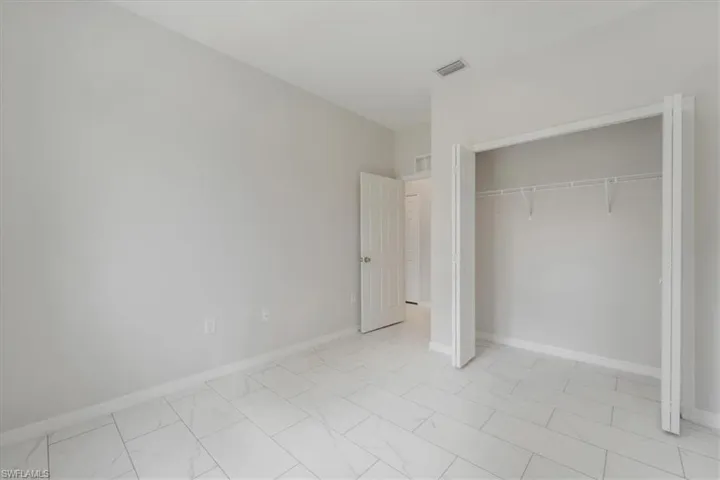 Unfurnished bedroom featuring a closet and light marble finish floors