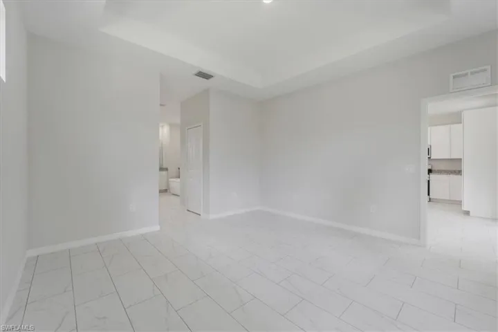 Unfurnished room with a raised ceiling and light marble finish flooring