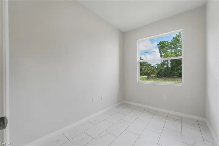 Empty room with light marble finish floors and lofted ceiling