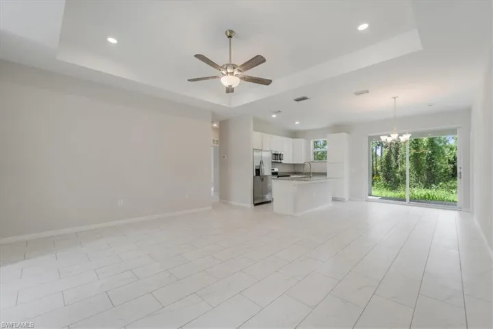 Unfurnished living room with hanging lights, a ceiling fan, and a raised ceiling