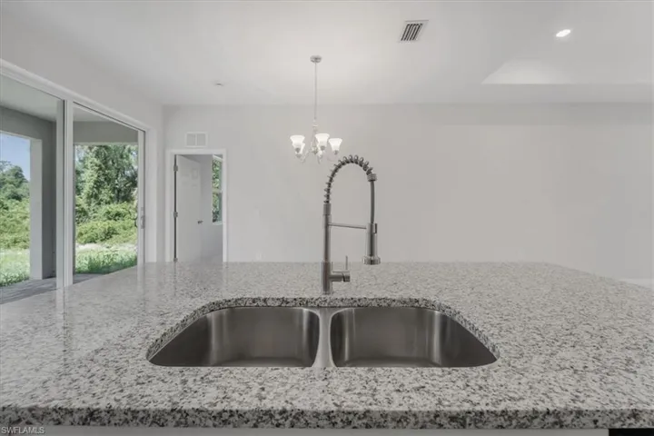 Kitchen view of light stone counters and suspended lighting