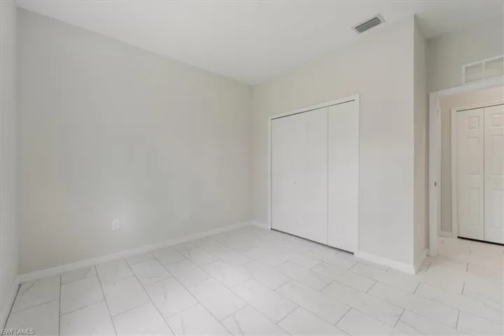 Unfurnished bedroom featuring a closet and light marble finish floors