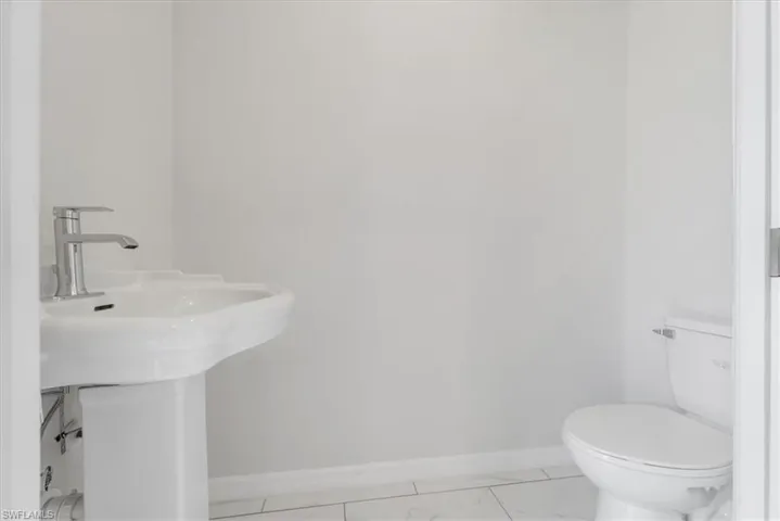 Half bathroom featuring baseboards and light marble finish flooring